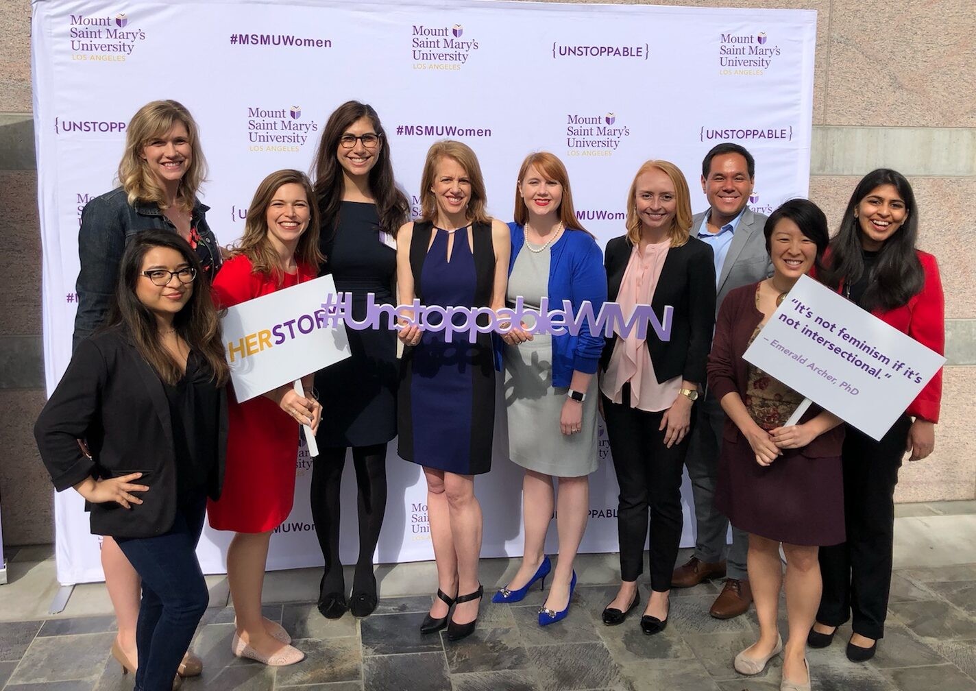 A photo of ten members of the Momentum team standing in front of a stand and repeat backdrop at the 2019 Report on the Status of Women and Girls in California