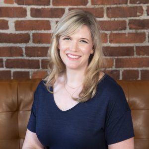 Kate Lehman portrait sitting on sofa wearing blue blouse.